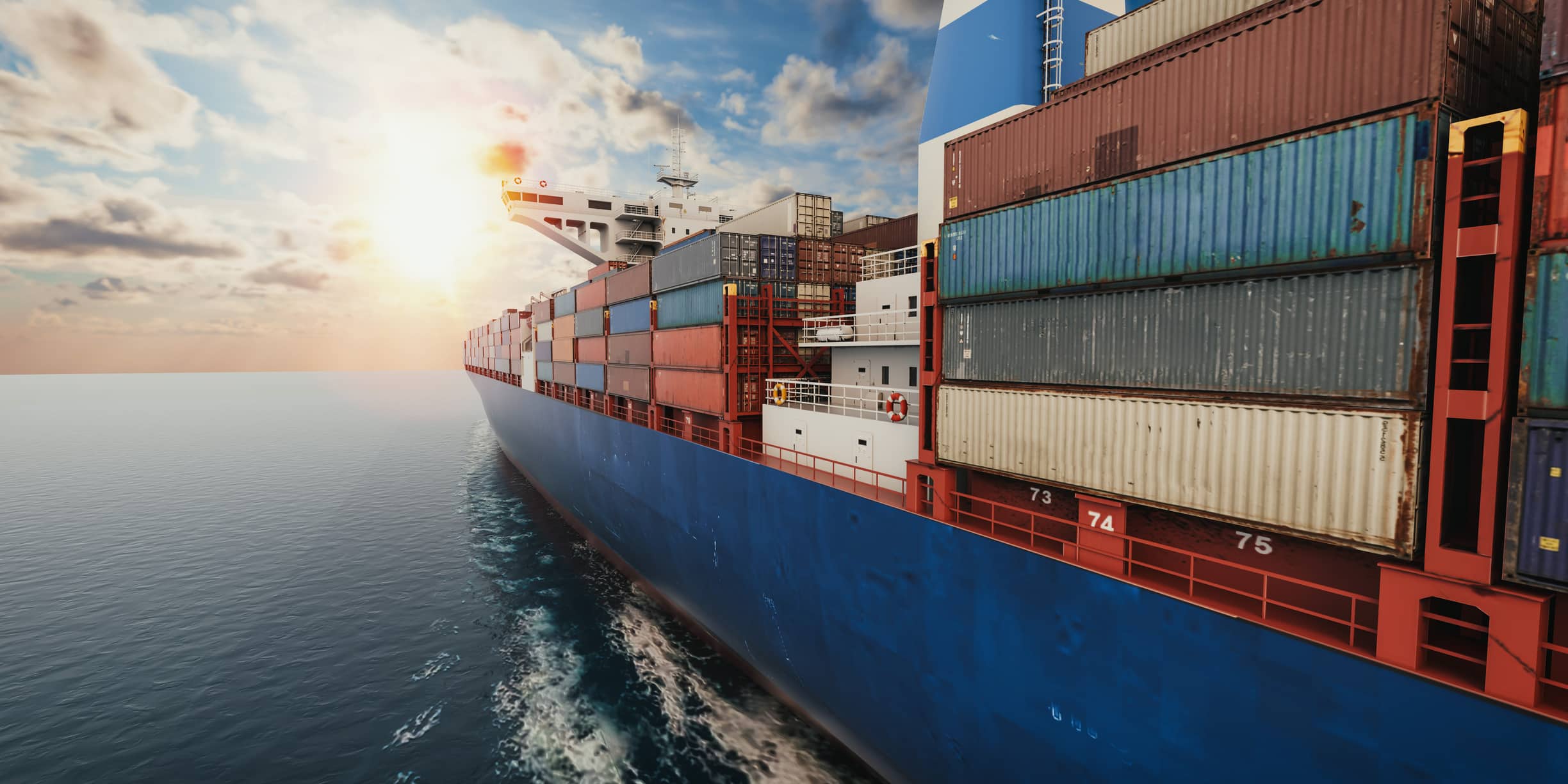 Container cargo ship sailing at sea during sunset, side view