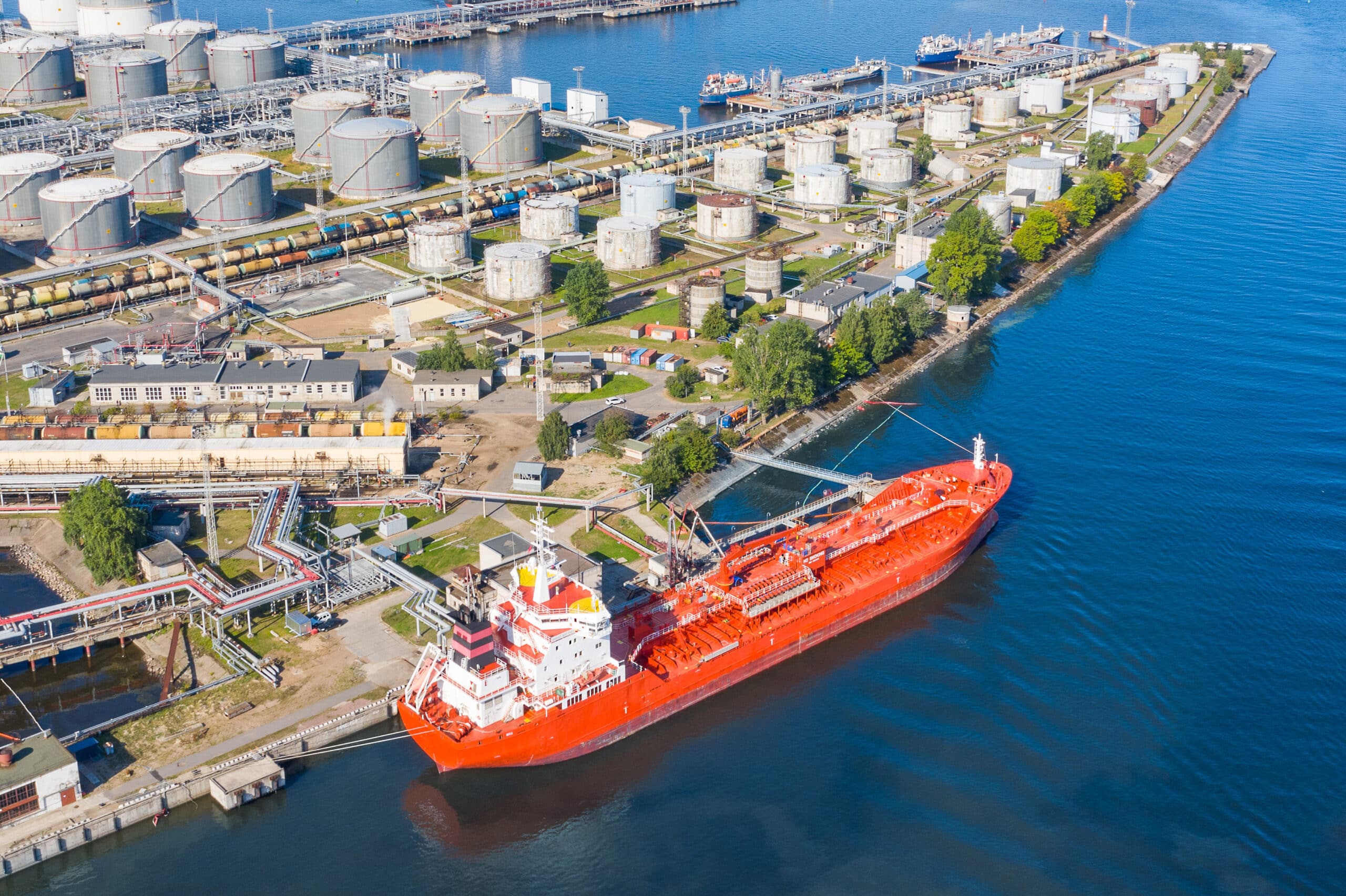 Aerial view large port oil loading terminal with large storage tanks. Railway infrastructure for the delivery of bulk cargo by sea, using pump station in ship tanker for transportation and delivery