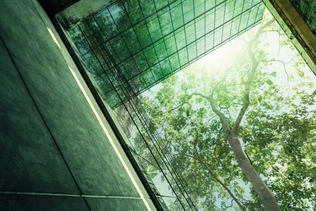 Sustainble green building. Eco friendly building in modern city. Sustainable glass office building with tree for reducing carbon dioxide. Office with green environment. Corporate building reduce CO2.