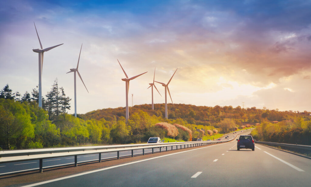 Cars going on highway in the landscape with wind propellers